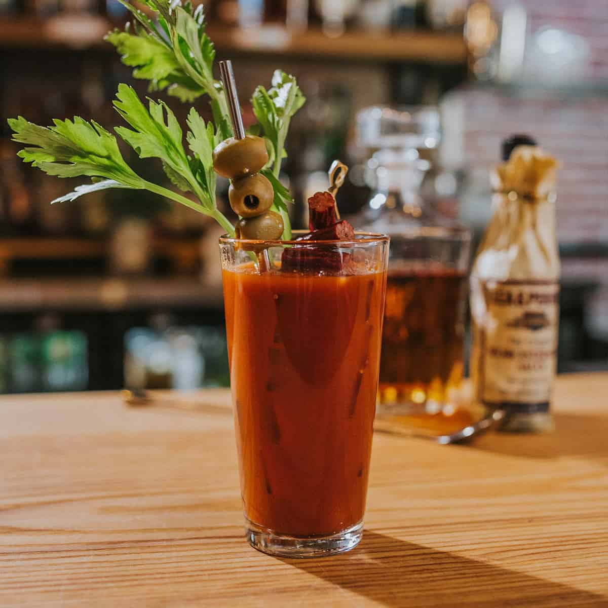 Bourbon bloody mary on a bar with celery, olives and beef jerky sticks