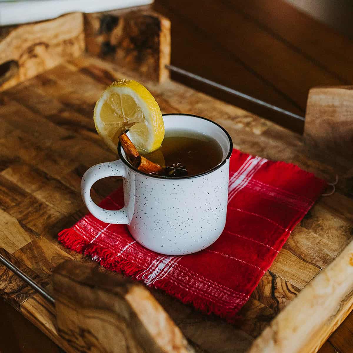 hot toddy cocktail in a mug with a lemon wheel and cinnamon sticks