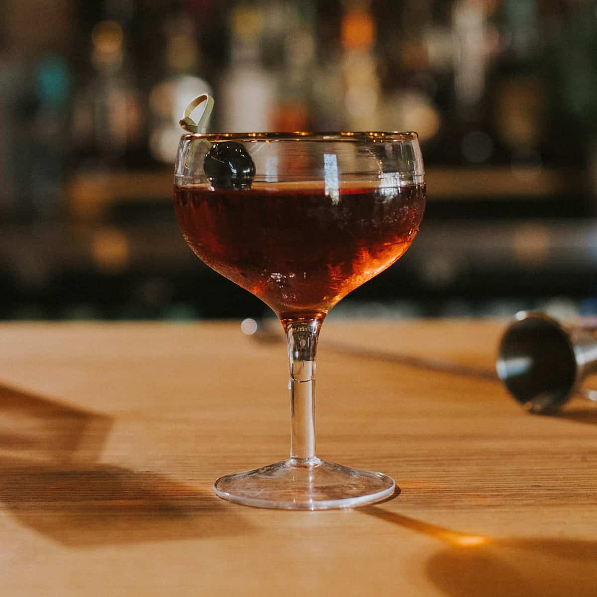 Manhattan cocktail on a bar with a brandied cherry